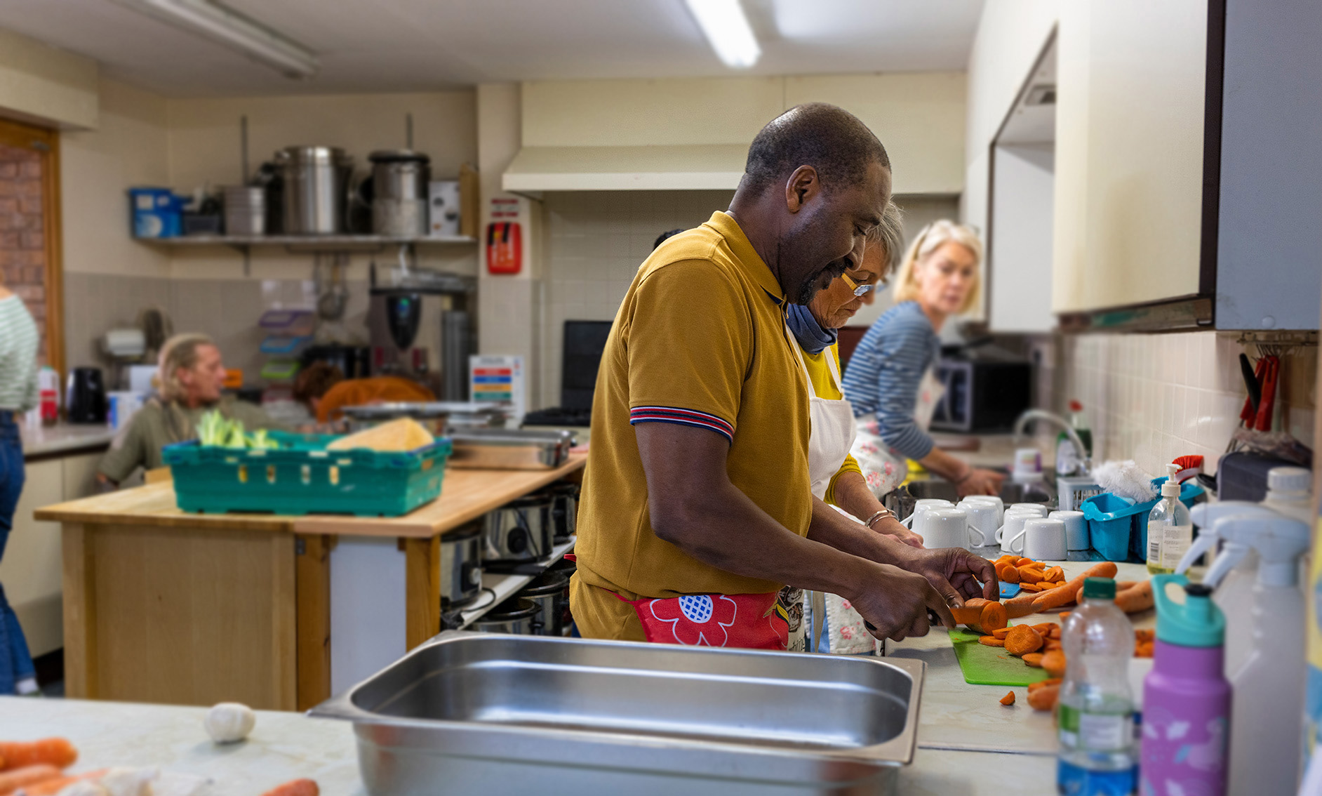 Black man and senior white woman chopping carrots in kitchen
