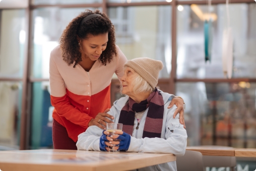Black woman with her hands on the shoulders of an elderly white woman who is seeking help